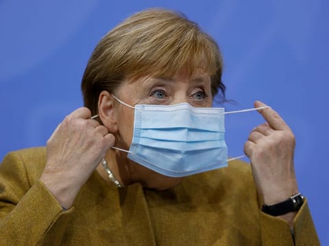 German Chancellor Angela Merkel takes off her face mask as she arrives for a press conference following  talks via video conference with Germany's state governors on extending coronavirus restrictions at the Chancellery in Berlin, Wednesday, Nov. 25, 2020.