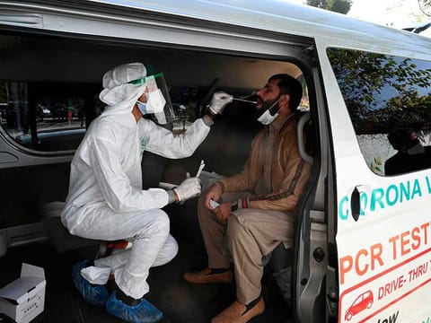 A health official collects a swab sample from a man to test for the COVID-19 coronavirus inside a van along the roadside in Islamabad. 