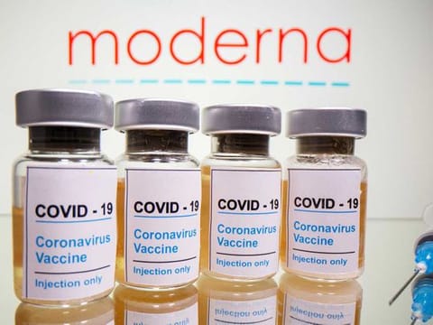 Vials with a sticker reading, "COVID-19 / Coronavirus vaccine / Injection only" and a medical syringe are seen in front of a displayed Moderna logo in this illustration taken October 31, 2020. 
