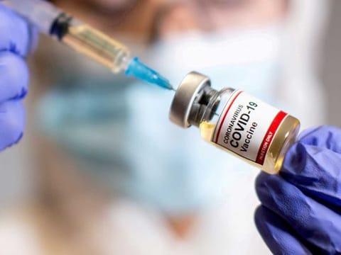 A woman holds a small bottle labeled with a "Coronavirus COVID-19 Vaccine" sticker and a medical syringe in this illustration taken  October 30, 2020. 