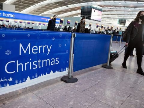 A passenger passes a 'Merry Christmas' sign in the check-in area in at London Heathrow.