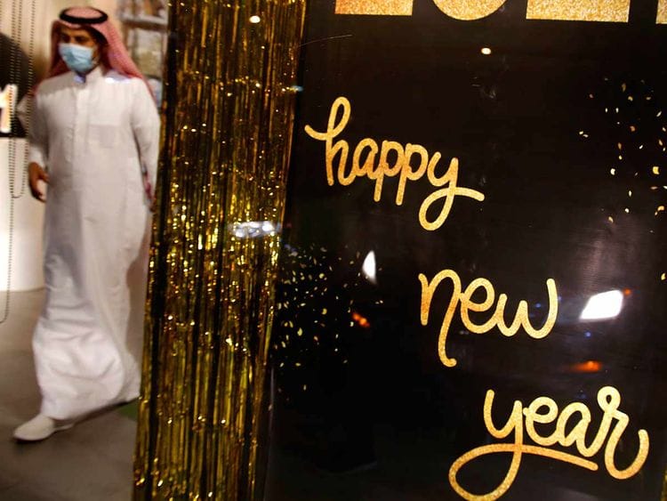 A man wearing a mask to protect from the coronavirus leaves a gift shop decorated for the New Year in Jiddah, Saudi Arabia, Friday, Dec. 25, 2020.