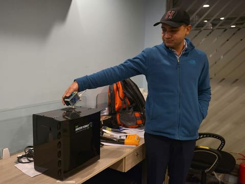 In this picture taken on December 6, 2019, inventor Hasan Zaidi checks the air quality next to his new air purifier device at the office of a customer in Lahore