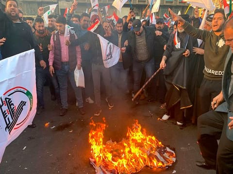  Protesters burn representations of a U.S. flag during a protest against the U.S. strikes on the Hezbollah Brigades militia, in Tahrir Square