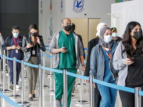 People queue as they arrive to register to be vaccinated for COVID-19 coronavirus at the make-shift vaccination centre erected at the Kuwait International Fairground in the Mishref suburb south of Kuwait City on December 29, 2020. 