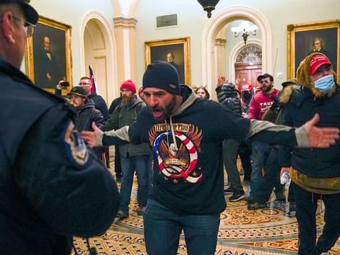 Trump supporters gesture to US Capitol Police in the hallway outside the Senate chamber after breaching the halls of the Capitol in Washington, Wednesday, Jan. 6, 2021. 