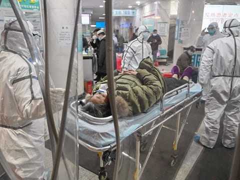 This file photo taken on January 25, 2020 shows medical staff members wearing protective clothing, arriving with a patient at the Wuhan Red Cross Hospital in Wuhan, in central China's Hubei province.  