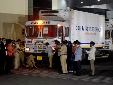 A police officer performs prayers in front of a truck carrying first consignment of Covishield, a coronavirus disease vaccine developed by AstraZeneca and Oxford University, before it leaves from Serum Bio-Pharma Park of Serum Institute of India, for its distribution, in Pune, on January 12, 2021. 