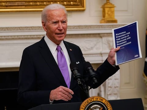 President Joe Biden holds a booklet as he speaks about the coronavirus in the State Dinning Room of the White House.
