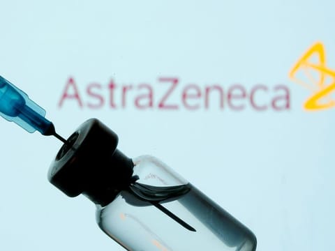 A vial and sryinge are seen in front of a displayed AstraZeneca logo in this illustration taken January 11, 2021. 