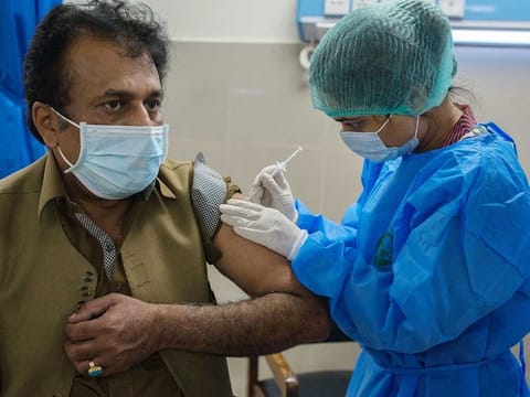 A health worker administers a COVID-19 vaccine to a colleague at the Dow University Hospital in Karachi, Pakistan
