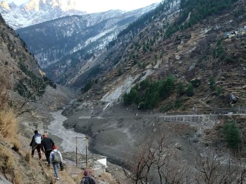 People walk past a destroyed dam after a Himalayan glacier broke and crashed into the dam at Raini Chak Lata village in Chamoli district, northern state of Uttarakhand, India, February 7, 2021.