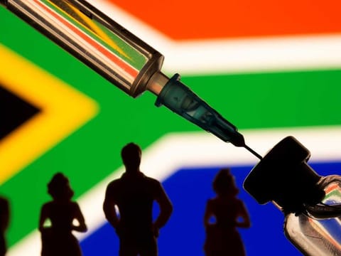 A vial, sryinge and small toy figures are seen in front of displayed South Africa flag in this illustration taken, February 9, 2021. 