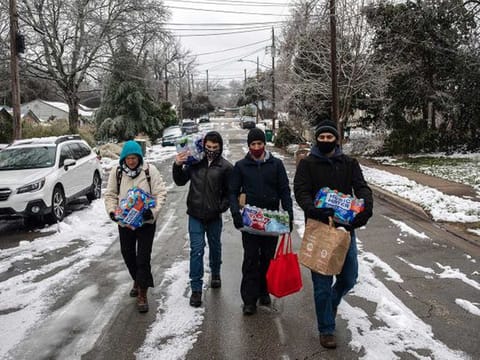 People walk back to their homes after buying packs of bottled water and other items from a convenience store in Austin, Texas 