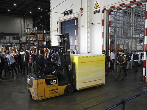 A worker moves a shipping container carrying doses of Covishield, the Indian-made Oxford/AstraZeneca vaccine against COVID-19, at Ezeiza International Airport in Buenos Aires, on February 17, 2021. 