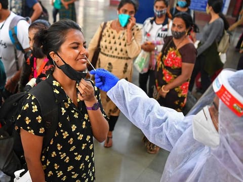 A health worker wearing protective gear takes a nasal swab sample of arriving passengers for conducting RT-PCR Covid-19 coronavirus tests during a screening at a railway terminus in Mumbai on February 22, 2021, as India's coronavirus cases passed 11 million.