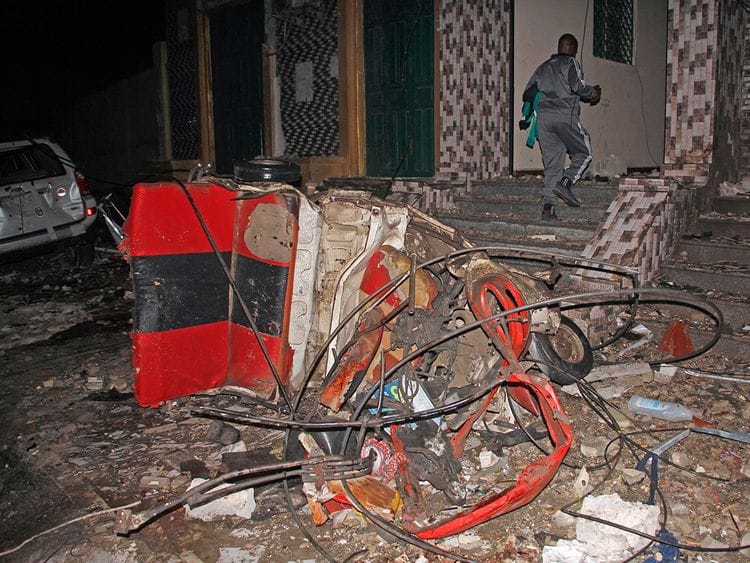 A man walks past a destroyed vehicle at the scene of a blast at a popular restaurant in the capital Mogadishu. 