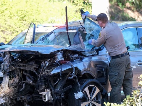 February 23, 2021 file photo: A law enforcement officer looks over a damaged vehicle following a rollover accident involving Tiger Woods in the Rancho Palos Verdes suburb of Los Angeles. 