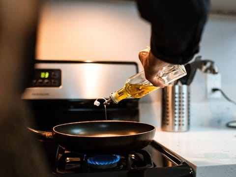 Oil is poured into a pan on a gas stove