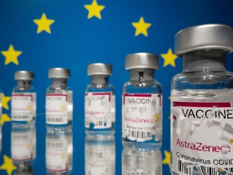 Vials labelled with partially torn sticker "AstraZeneca COVID-19 Coronavirus Vaccine" are seen in front of a displayed EU flag in this illustration. REUTERS