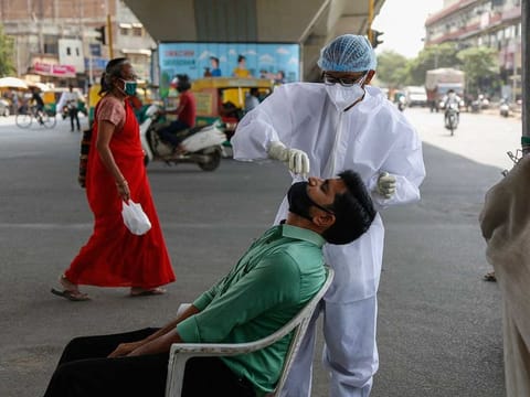 A health worker takes a nasal swab sample of a man to test for COVID-19 at a busy street in Ahmedabad, India, Wednesday, March 17, 2021. 