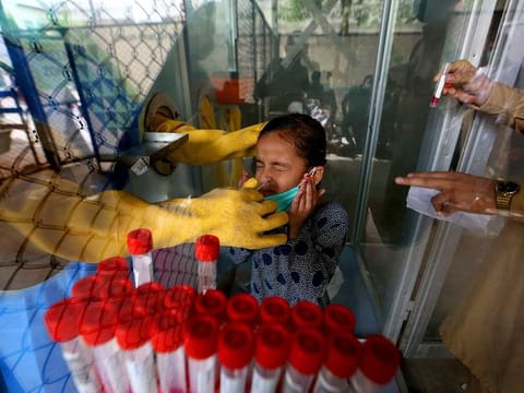 A young girl reacts while having a nasal swab sample taken by a health worker at a COVID-19 testing facility in a hospital in Karachi, Pakistan.