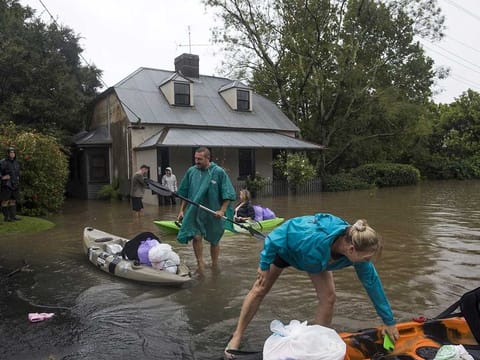 Residents unload household items from kayaks at a street submerged in floodwaters in Windsor, New South Wales, Australia, on Monday, March 22, 2021.