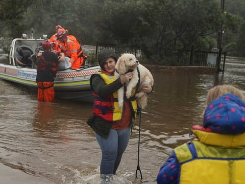 A woman and dog rescued by a State Emergency Service crew make it to safety after being trapped by rising floodwaters, as the state of New South Wales experiences widespread flooding and severe weather, in the suburb of Sackville North in Sydney, Australia, March 23, 2021. 