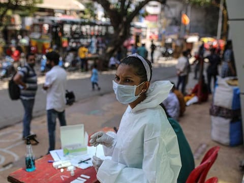 A healthcare worker conducts a test at a rapid-antigen methodology COVID-19 test site set-up outside the Star Mall in the Dadar area of Mumbai, India, on Wednesday, March 31, 2021. 