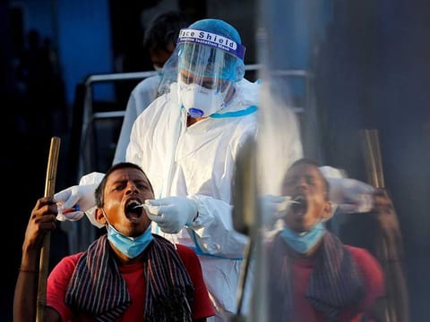 A healthcare worker collects a coronavirus disease (COVID-19) test swab sample from a man, at a temporary shelter for homeless people in New Delhi, India, March 31, 2021.