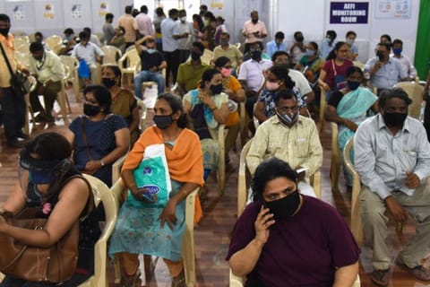 People wait in observation room to receive a dose of the Covishield, AstraZeneca-Oxford's Covid-19 coronavirus vaccine at a vaccination centre during a weekend lockdown imposed by the state government amidst rising COVID-19 cases, in Mumbai on April 10, 2021. 