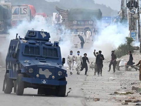 Supporters of Tehreek-e-Labbaik Pakistan (TLP) party throw stones over the police armoured vehicle during a protest against the arrest of their leader as he was demanding the expulsion of the French ambassador over depictions of Prophet Mohammed (PBUH), in Barakahu neighbourhood of Islamabad on April 13, 2021. 