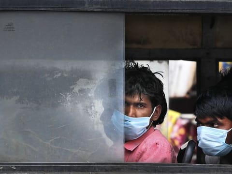 Migrant laborers sit in a bus to travel to their villages following a lockdown put into place to control the rising cases of coronavirus infections, in New Delhi, India, Tuesday, April 20, 2021