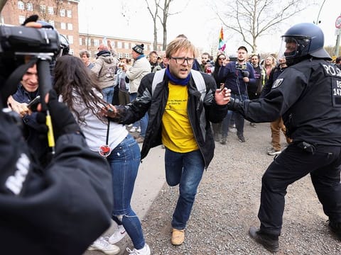 A demonstrator runs past a police officer during a protest against the government measures to curb the spread of the coronavirus disease (COVID-19), on the day of discussion in the lower house of parliament Bundestag regarding additions for the Infection Protection Act, in Berlin, Germany April 21, 2021. 