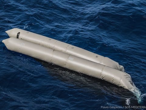 A rubber boat is seen after having capsized with more than 100 migrants on board, during a search and rescue (SAR) operation in the Mediterranean Sea, off the Libyan Coast.