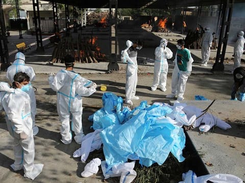 People remove their protective suits after performing the final rites of a relative who died of COVID-19 at a crematorium in Jammu, India, Friday, April 23, 2021. 