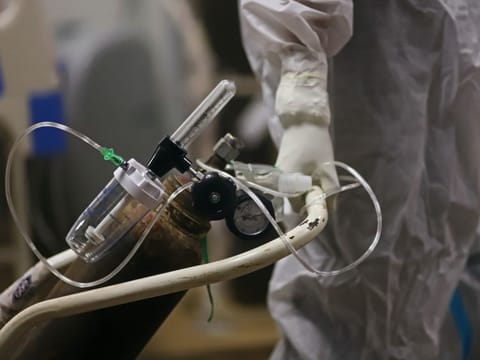 A health worker wheels an oxygen canister in a COVID-19 hospital set up inside a stadium in New Delhi, India, on Friday, April 23, 2021. Bodies piling up at crematoriums and burial grounds across India are sparking concerns that the death toll from a ferocious new COVID-19 wave may be much higher than official records, underplaying the scale of a resurgence that is overwhelming the country’s medical system. 
