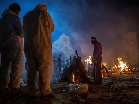 People cremate bodies of victims of coronavirus at a crematorium in New Delhi, India