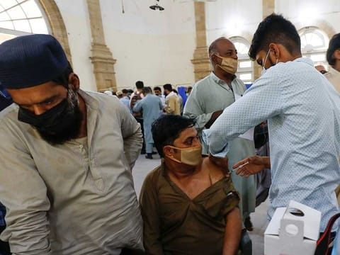 A man receives a dose of the coronavirus disease (COVID-19) vaccine, as others wait for their turn, at a vaccination center in Karachi, Pakistan April 28, 2021. 