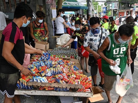 Residents collecting free food packets from a food bank called a "community pantry", run by volunteers, along a road in Quezon City in suburban Manila
