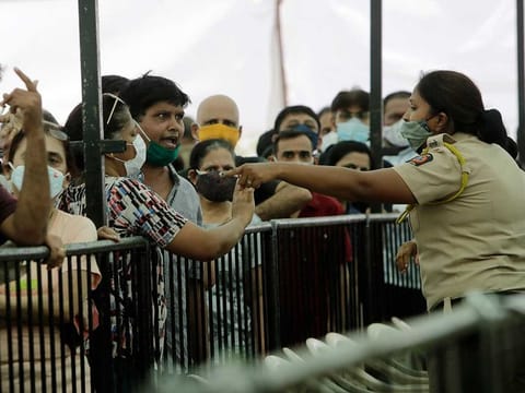 A man argues with a policewoman as he waits with others to receive COVID-19 vaccine outside a vaccination centre in Mumbai, India