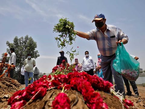  A man scatters leaves and flower petals on the grave of 65-year-old Arnold Samuel Christian, who died from the coronavirus disease (COVID-19), after his burial at a cemetery in Ahmedabad, India, May 3, 2021. 