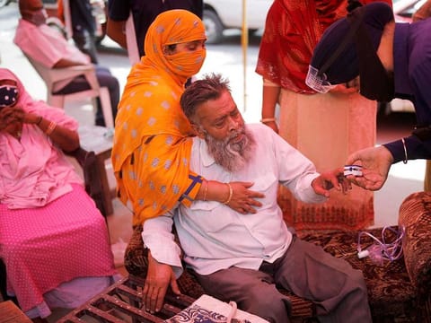 A volunteer uses a pulse oximeter to check the oxygen saturation of a man's blood before providing him oxygen support for free at a Gurudwara (Sikh temple), amidst the spread of coronavirus disease (COVID-19), in Ghaziabad, India, May 3, 2021. 