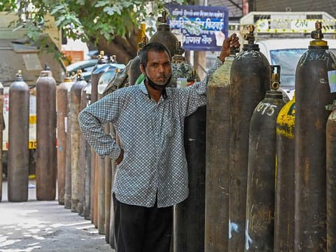 A man waits to refill his medical oxygen cylinder for a COVID-19 coronavirus patient under home quarantine at a private refill centre in New Delhi on May 4, 2021, as India's total COVID-19 caseload soared past 20 million. 