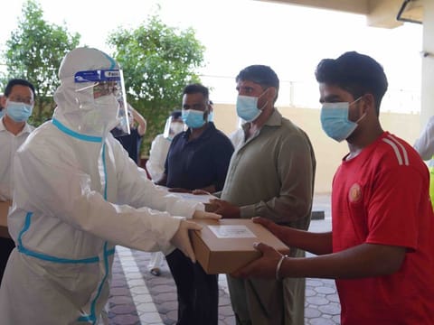 Chinese Consul-General Li Xuhang hands over iftar meal packs at a workers' accommodation in Dubai during Ramadan. 