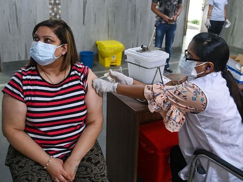 A health worker inoculates a woman with a dose of the Covishield Covid-19 coronavirus vaccine at a vaccination centre in New Delhi on May 13, 2021. 