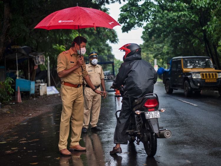 A police officer holds an umbrella to protect himself from the rain as he enforces a lockdown to curb the spread of the coronavirus in Kochi, Kerala state, India, Sunday, May 16, 2021. 
