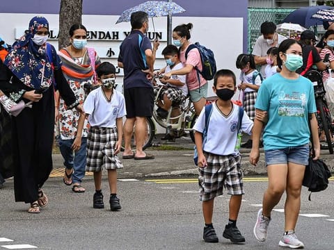 Children walk home with their guardians after school in Singapore on May 17, 2021, as the country prepares to shut all schools and switch to home-based learning until the end of the term due to a rise in the number of Covid-19 coronavirus cases. 
