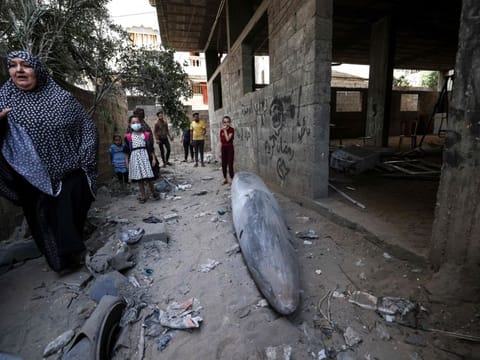 A Palestinian woman stands next to an unexploded bomb dropped by an Israeli F-16 warplane on Gaza City's Rimal neighbourhood on May 18, 2021. 