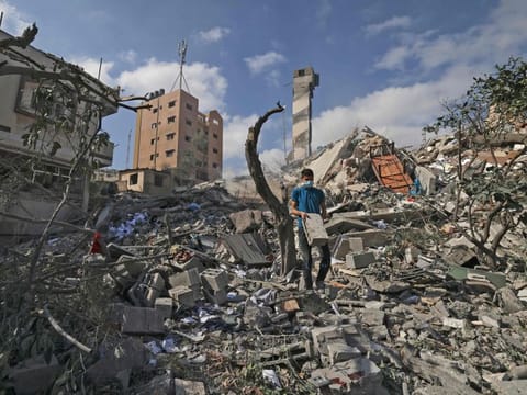 TOPSHOT - A Palestinian youth looks for salvageable items amid the rubbe of the Kuhail building which was destroyed in an early morning Israeli airstrike on Gaza City on May 18, 2021. 
